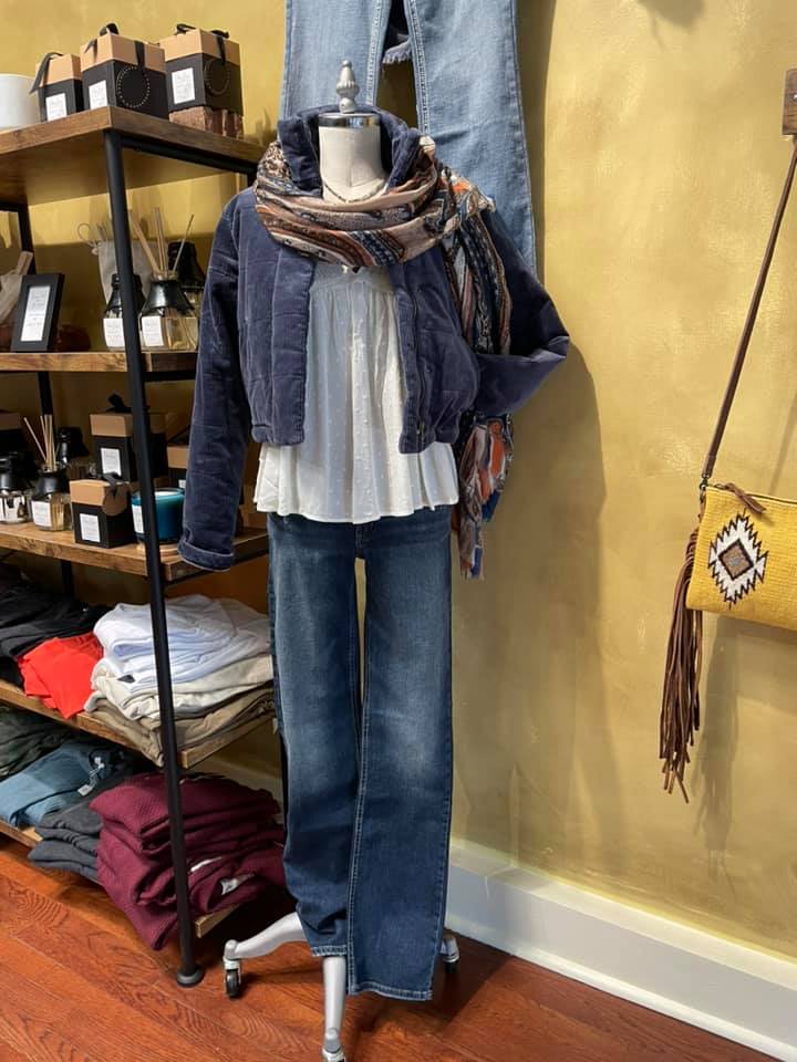 Display of a casual outfit -blue jeans, white blouse, jacket, and a scarf